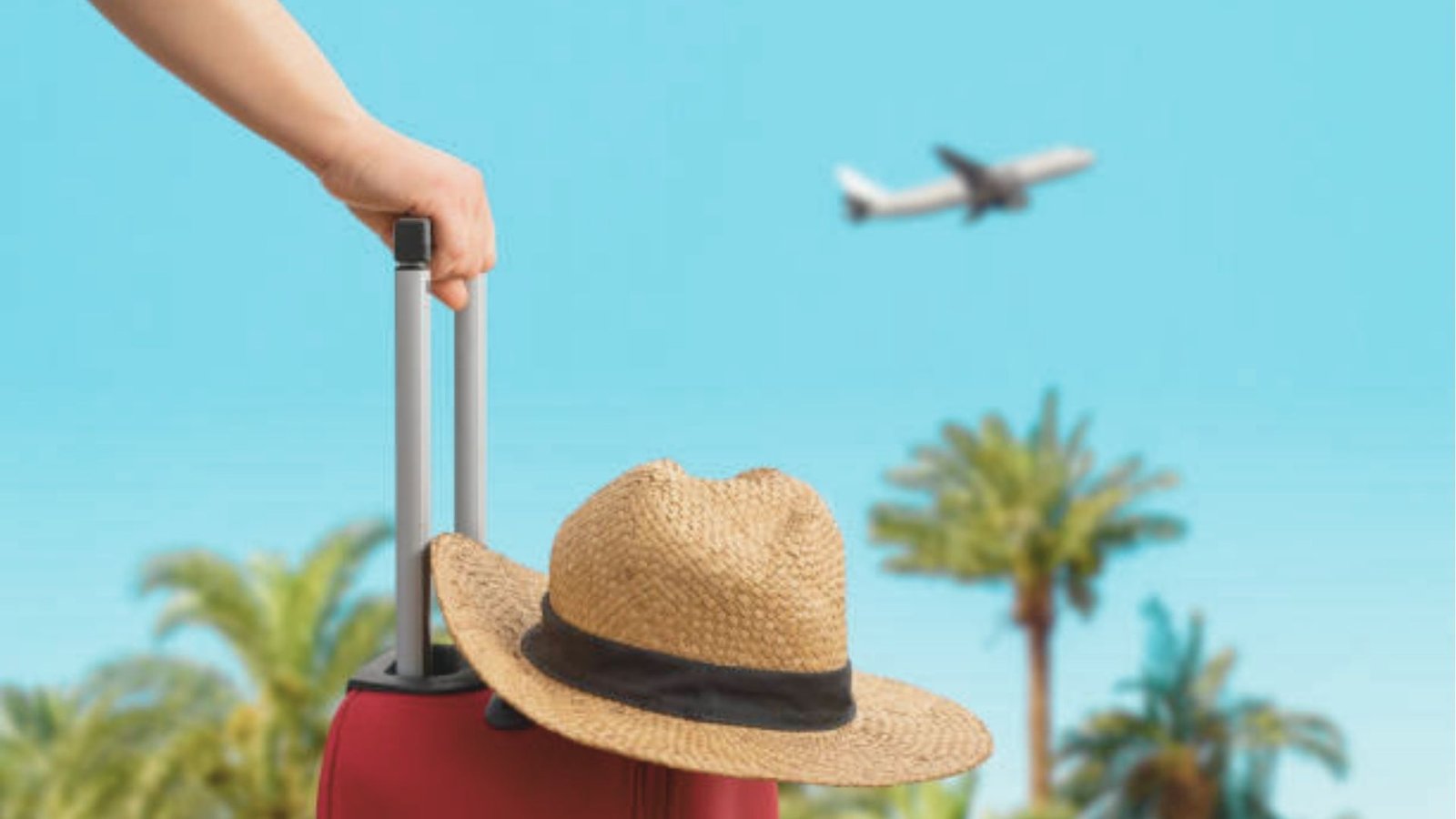 Person holding a red rolling suitcase with a straw hat hanging on the handle, palm trees and an airplane in a clear blue sky.